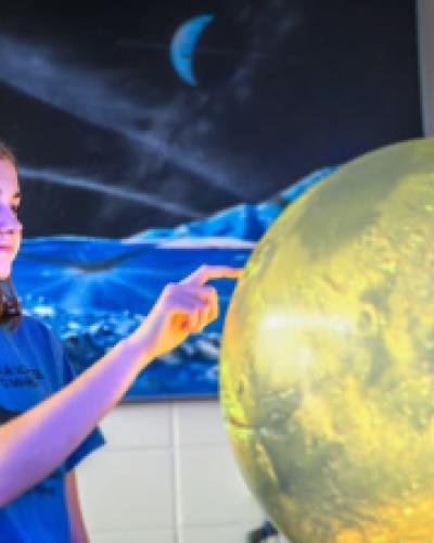 A student interacts with a planetary model